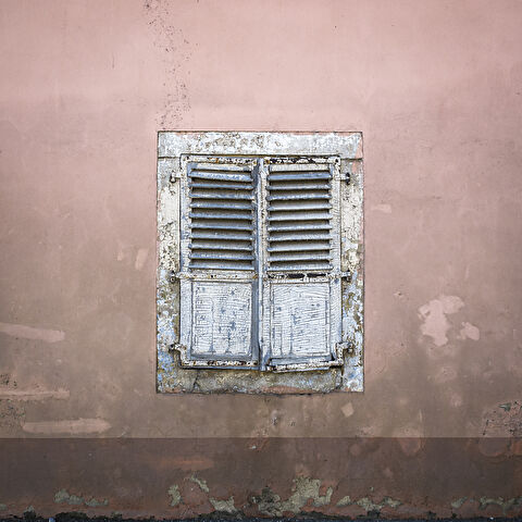 Vieille façade de ferme avec sa fenêtre occulté par des volets.