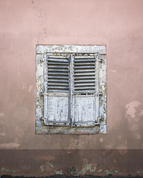 Vieille façade de ferme avec sa fenêtre occulté par des volets.